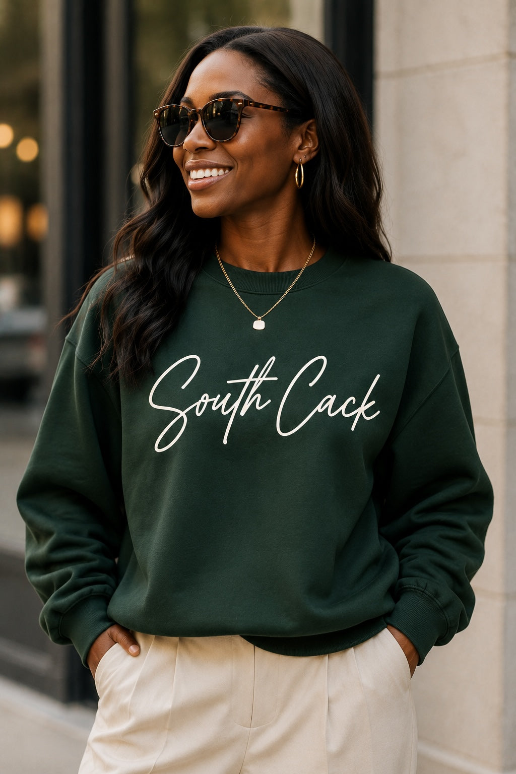 A woman wearing a saysomethingteez dark green crewneck sweatshirt with white South Cack script text on the chest.
