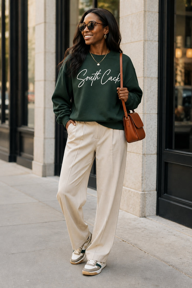 saysomethingteez dark green South Cack crewneck sweatshirt worn by a woman with beige trousers and sneakers