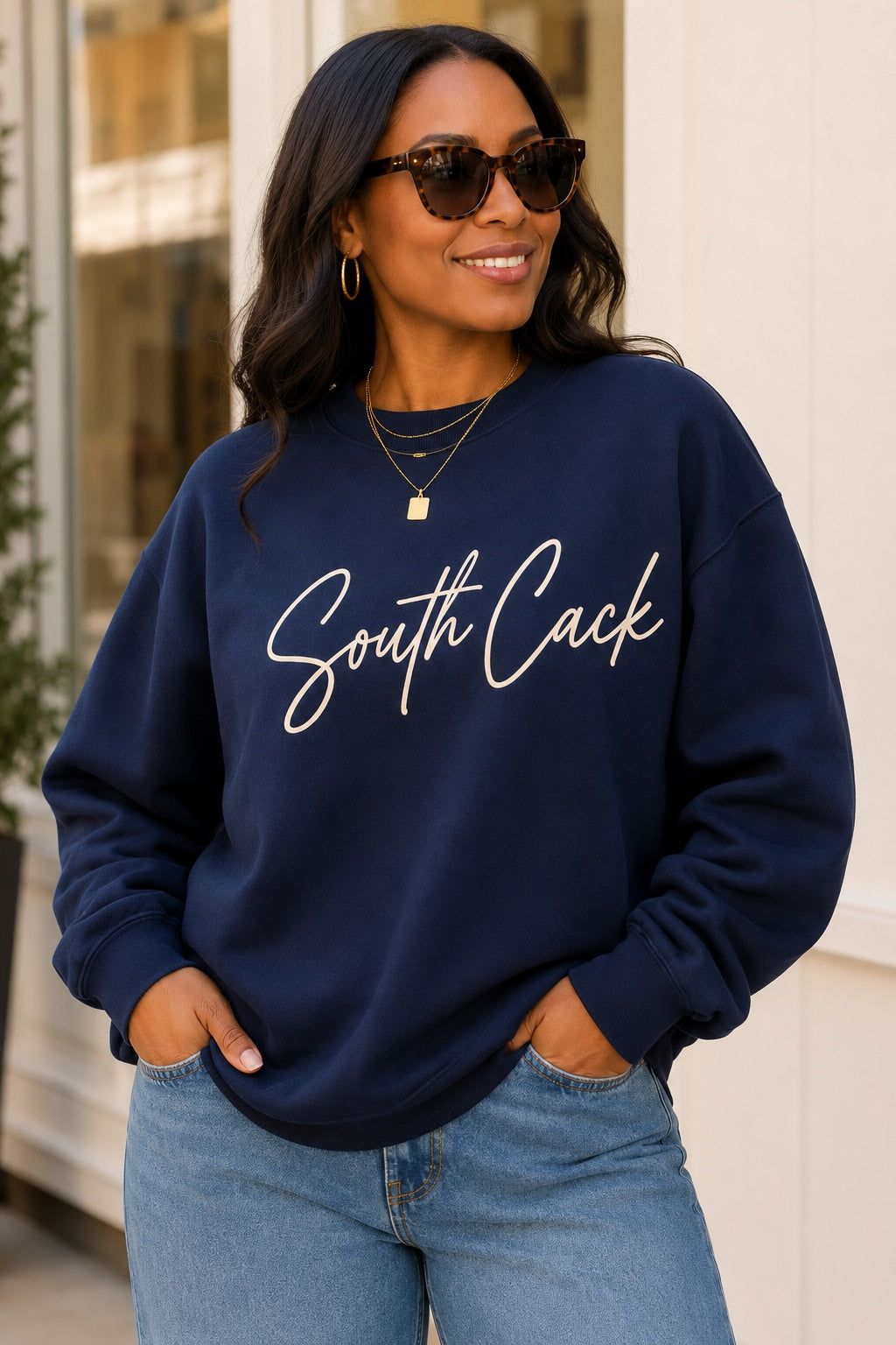 Woman wearing a navy blue saysomethingteez South Cack crewneck sweatshirt with script lettering and jeans